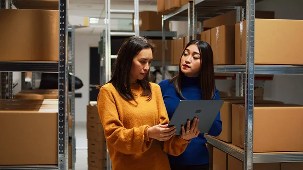 亚洲妇女在仓库进行财务规划 在笔记本电脑上查看库存 企业家和工人检查订单和分配管理 用品堆栈 — 图库照片