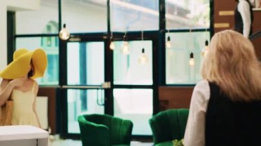 Otel lobisindeki resepsiyona yaklaşan bayan müşteri, resepsiyon görevlilerine yaz tatilindeki tropik tatil için oda rezervasyonunu soruyor. Kadın tramvay çantalarıyla dinlenme odasına giriyor..