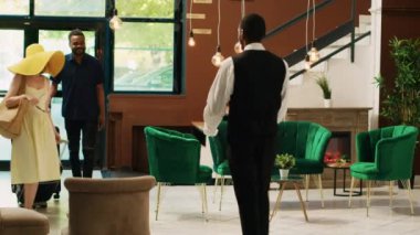 Otel komileri resepsiyona giren konuklara lüks hizmet sunuyor. Bagaj ve yük çantalarını odaya taşıyan kapıcı. Genç bir çift tropik tatil köyüne geliyor..