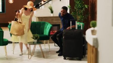 Otelin lobisindeki lobide oturan turistler kontrol işlemleri ve kayıt formlarını doldurmak için bekliyorlar. Balayı için egzotik sahil tatil köyüne gelen çift, kapıcı servisi..