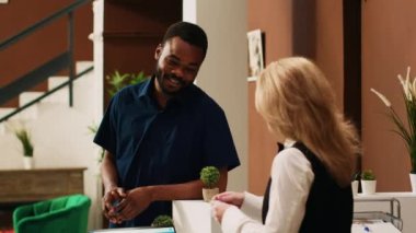 Gezgin resepsiyonistten oda kartı alıyor, egzotik yaz oteline vardığında kalacak yerin anahtarını alıyor. Genç misafir kayıt işlemini resepsiyonda tamamlıyor. El kamerasıyla..