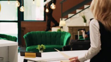 Lobideki egzotik otel misafiri resepsiyonistle kayıt işlemlerini halletmek için bekliyor. Tropikal deniz kıyısındaki bir kadın uluslararası yaz tatiline geliyor..