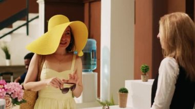 Otel resepsiyonuna gelen kadın tropik sahil beldesindeki oda rezervasyonundan bahsediyor. Yaz gezgini egzotik adalar oteline giriş yapıyor, uluslararası tatil.