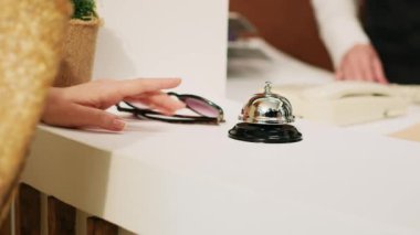 Sabırsız misafir tezgahtaki servis zilini çalıp oteldeki resepsiyon görevlilerinden yardım istiyor. Tropikal tatil beldesinde yaz tatili için bekleyen bir turist. El kamerasıyla. Kapat..