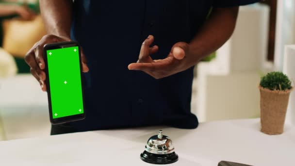 男性游客手持带有绿色屏幕的手机 指向展示的彩色图标模板 非洲裔美国人持屏幕 接待处前台有独立的复制空间 — 图库视频影像