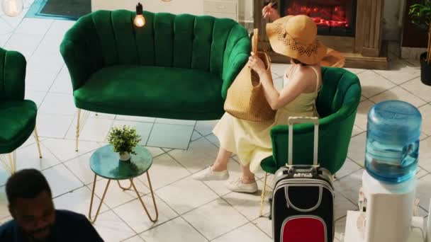 女性のお客様が彼女の部屋に荷物を運ぶのを助けるベルボーイ ラウンジエリアで待っているトロリーバッグを持つ旅行者 ホテルのお客様に豪華なサービスを提供するプロのベルホップ 手持ち撮影 — ストック動画