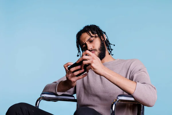 Homem Árabe Focado Com Deficiência Jogando Videogame Smartphone Enquanto Sentado — Fotografia de Stock
