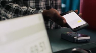 Afrika kökenli Amerikalı müşteriler butikte moda kıyafetlerin parasını ödemek için telefon açıyor. İşçilerle kumaşı tartıştıktan sonra. Perakende satış tezgahında duran adam şık ürünler alıyor.