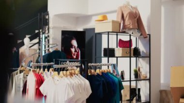 Moda mağazasında asılı günlük giyim eşyalarıyla donatılmış boş bir alışveriş merkezi. Modern butikte indirimli ürünler ve aksesuarlarla dolu raflar ve askılar. Moda konsepti