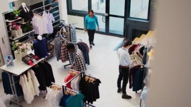Üst düzey müşteriler şık kıyafetleri kontrol ediyor, modern butikte moda ürünler ve aksesuarlar satın alıyor. Müşteriler askıları yeni moda koleksiyonuyla analiz ediyor