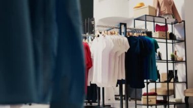 Alışveriş merkezinde boş modern butik, raflarda yeni moda koleksiyonu. Askılarda şık kıyafetler, giyim mağazası müşterilere indirimli ürünler ve aksesuarlar.