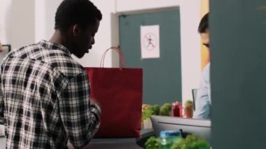 Çalışanlar, giyim mağazasında pahalı mallar aldıktan sonra müşterilerine kese kağıdı veriyor. Afrika kökenli Amerikalı alışverişçi modern butikte şık kıyafetler ve moda aksesuarlar satın alıyor.