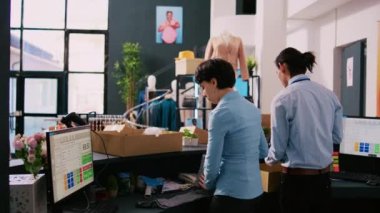 Çeşitli işçiler çevrimiçi siparişler hazırlıyor, moda kıyafetleri giyim mağazasındaki karton kutulara koyuyorlar. Paket teslimatında çalışan butik çalışanları, alışveriş merkezindeki müşterilere nakliye