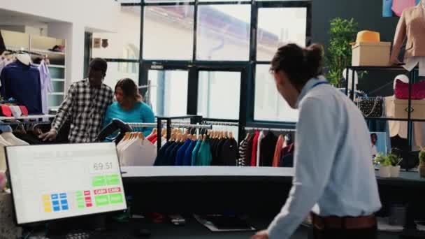 Trabalhador Loja Ajudando Casal Com Roupas Moda Mostrando Cabides Com — Vídeo de Stock
