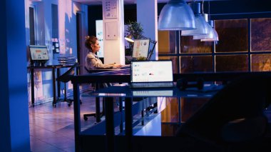 Genç iş kadını şirket ofisindeki çevrimiçi analizleri kontrol ediyor, geceleri iş geliştirme planları yapıyor. Pazarlama raporu oluşturmak için finansal grafiklere bakan kadın yönetici. El kamerasıyla..