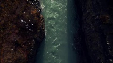 İzlanda 'daki görkemli şelale manzarası tepelerden akan nehir akıntısı donmuş tarlalar ve manzaralar. Su akıntısı ve kanyon kayalarıyla muhteşem bir İzlanda doğası. 60 fps video.