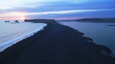 Atlantik kıyısındaki Reynisfjara plajının hava manzarası İzlanda 'daki görkemli siyah kum plajı. Devasa uçurumlar Reynisfjall Dağı 'nın güzel manzarasını ve manzarasını oluşturuyor. 60 fps video.