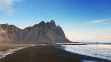 Stoksnes sahilinin insansız hava aracı görüntüleri, İzlanda yarımadasındaki siyah kumlu Vestrahorn dağları. Yol kenarındaki güzel İskandinav manzarası, panoramik manzara. 60 fps video.