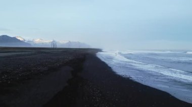 Atlantik kıyısı kara kum plajı, Kuzey kıyılarına vuran dalgalar İzlanda 'da doğal bir manzara yaratıyor. Güzel İzlanda manzarası ve kutup panoramik manzarası. 60 fps video.