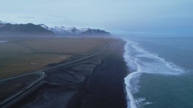 İzlanda 'daki Nordic Black Kum Sahili' nin insansız hava aracı görüntüleri, karlı dağlarla dolu kutup okyanus kıyısı manzarası. Atlantik kıyısında panoramik manzaralı güzel İzlanda manzarası. 60 fps video.