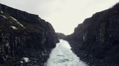 Gullfoss Şelalesi Kanyonu 'nun havadan görünüşü. Su akıntısı ve donmuş tepeleri olan görkemli kuzey manzarası. İzlanda 'daki muhteşem şelale kayalıklardan aşağı akıyor. 60 fps video.