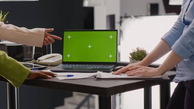 İş arkadaşlarından oluşan bir ekip, iş birliği veya ortaklık için izole edilmiş bir model gösterimi üzerinde çalışarak, dizüstü bilgisayardaki yeşil ekran şablonuna bakıyor. Ortak çalışma odasında oturan insanlar ve kopyalanan alan.