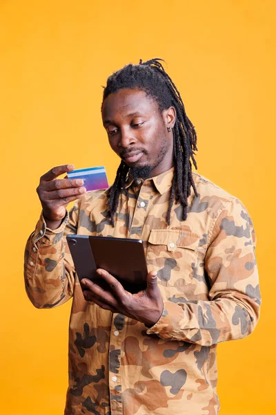 非裔美国人在工作室进行网上购物 从时尚商店订购时尚服装 微笑的年轻人浏览网上银行服务 在电话上输入信用卡信息 — 图库照片