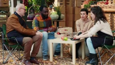 Mutlu bir grup arkadaş yerel gıda pazarında ürün örnekleme yapıyor, fuarda buluşuyorlar. Çeşitli insanlar organik sulu elmaların tadını çıkarıyorlar, çiftçilerle ev yapımı şarap içiyorlar. El kamerasıyla..