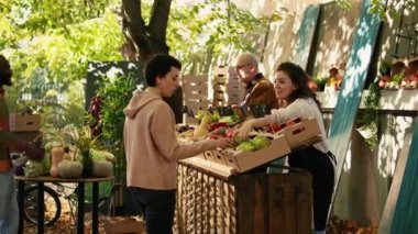 Genç satıcı müşterilerine bedava elma numunesi veriyor, yerel markette taze ürünlerden örnek alarak eğleniyor. Müşterilere vermek için meyve kesen bir kadın, küçük işletme sahibi..