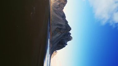 Dikey video: Stoksnes sahilinin insansız hava aracı görüntüleri, İzlanda yarımadasındaki siyah kumlu vestrahorn dağları. Yol kenarındaki güzel İskandinav manzarası, panoramik manzara. 60 fps video.