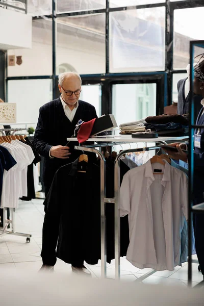 Starszy Mężczyzna Szuka Ubrań Wieszakach Sprawdza Tkaniny Koszulowe Sklepie Odzieżowym — Zdjęcie stockowe