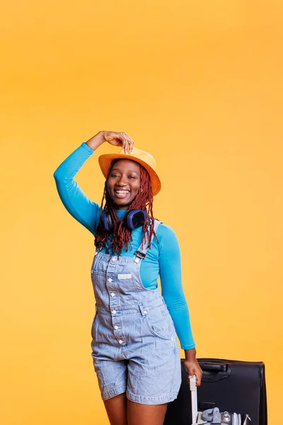 Αφροαμερικανή Που Χαμογελάει Στο Στούντιο Και Κουβαλάει Αποσκευές Τρόλεϊ Νιώθοντας — Φωτογραφία Αρχείου