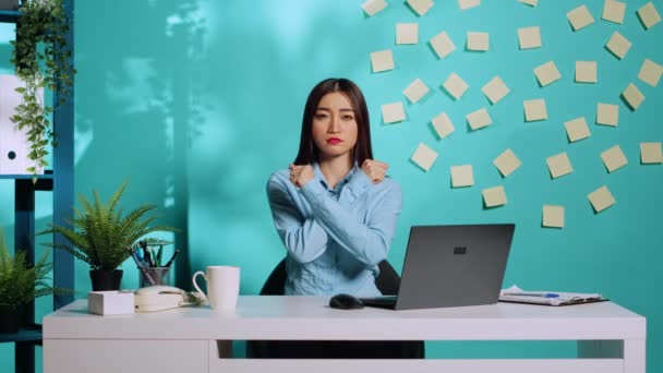 アジア系の従業員は 彼女の立場に自信がなく X記号で2本の交差した腕を保持していると主張しています 動揺したが決定された事務員ストレスの多い労働条件を拒否 — ストック動画
