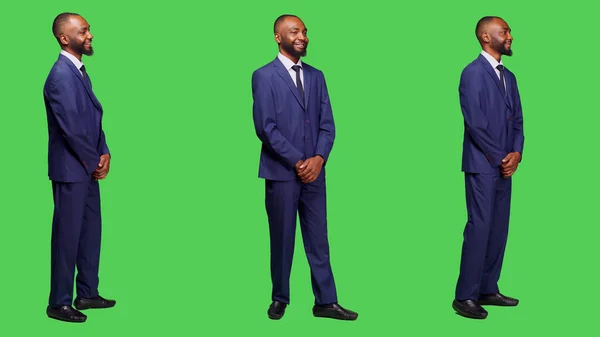 スタジオでオフィススーツを着た笑顔の社員は 全身緑色の画面を背景に自信を持って立ってポーズをとっています 若い正の実業家の感情は愚かで自信がある — ストック写真