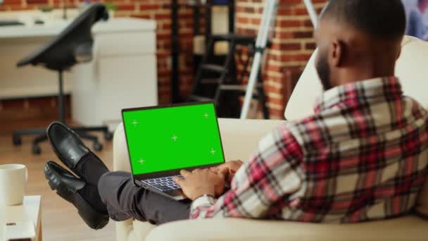 アフリカ系アメリカ人の男性は ソーシャルメディアでオンラインの友人とチャットし クロマキーを見てノートパソコンの緑の画面をモックアップします キーボードでメッセージを入力し インターネット上の仲間と議論する人 — ストック動画