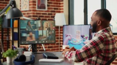 Gülümseyen tele-çalışan yönetici şık bir dairede oturmuş çevrimiçi video görüşmesi sırasında iş arkadaşlarıyla konuşuyor. Neşeli yönetici uzaktan çalışan ekiple video konferansı düzenliyor.