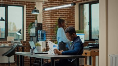 İş arkadaşları masa başında veri raporlarını analiz ediyor, yeni proje planlamak için belgelerdeki iş bilgilerini gözden geçiriyorlar. Ortak çalışma alanındaki geliştirme stratejisini tartışan bir grup insan.