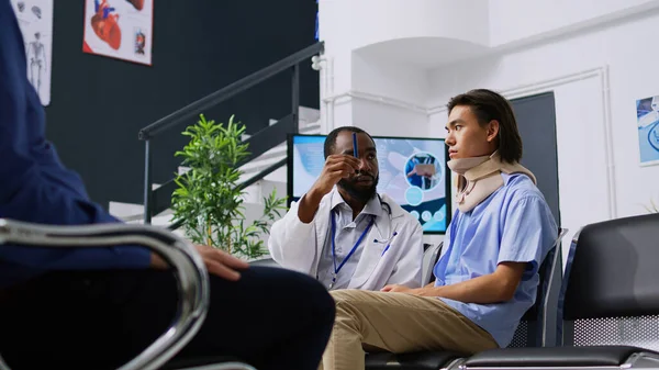 医生在医院候诊室检查病人的视力 在检查期间讨论保健治疗 亚洲男人戴颈圈 在接待处接受医疗支援 — 图库照片