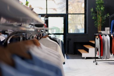 Alışveriş merkezindeki boş giyim mağazası, raflarda yeni moda koleksiyonu. Askılarda ve aksesuarlarda şık kıyafetler, müşteriler için indirimli ürünleri olan modern butik.