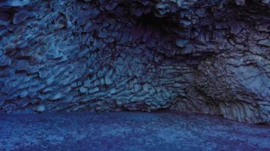 Reynisfjara sahilindeki bazalt taş yığınları, Reynisfjall dağındaki duvarlara istiflenmiş siyah kaya oluşumları. Görkemli İzlanda doğası muhteşem bir manzara yaratıyor, siyah kumsal..