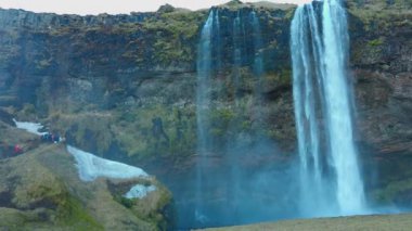 Seljalandsfoss, İzlanda - 4 Mart 2023 - İzlanda 'da güzel bir şelale, uçurumdan aşağı akan görkemli bir nehir. Dağları ve tepeleri olan İskandinav çağlayanı. El kamerasıyla..
