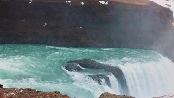 北欧の荒野のガルフクロス滝 雪原と凍る水が崖から落ちる壮大なアイスランドの風景 丘の上の北極の風景は アイスランドのカスケード 手持ち撮影 — ストック動画