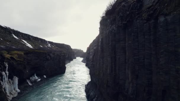 アイスランドのガルフフォスカスケード 岩の多い丘や崖の間を流れる壮大な水の流れのドローンショット 冬の風景をオフに実行しているアイスランドの美しい滝 スローモーション — ストック動画