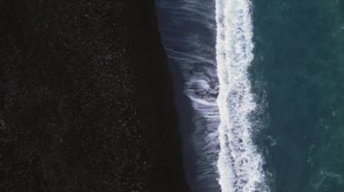 İzlanda siyah kumlu plaj hava manzarası, kıyı şeridine dalgaların çarptığı muhteşem Atlantik kıyıları. Kutup manzarası, karlı dağlar ve kumsaldaki siyah kumlar, soğuk manzaralar. Yavaş çekim.