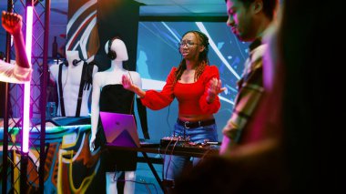 Çılgın DJ partide müziği karıştırmak için sahnede karışık kanalı kullanıyor. Diskotekte farklı insanlarla eğleniyor. Neşeli, havalı bir kadın parti yapıyor ve kulüpte müzik seti kullanıyor. El kamerasıyla..