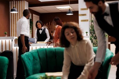 Afrikalı Amerikalı çift oteldeki resepsiyondaki kızla konuşuyor, konaklama detaylarını gözden geçiriyorlar ve kayıt yapıyorlar. Yapmayı bekleyen gençler formları kontrol ediyorlar.