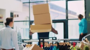 Afro-Amerikan kurye karton kutularla dolu yığını modern butikte mağaza müdürüyle nakliye detaylarını tartışıyor. Teslimatçı tablet bilgisayarda sevkiyat raporunu imzalıyor. Moda konsepti