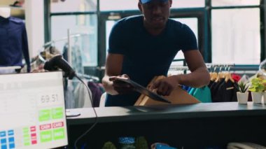 Modern butikte teslimat için paket hazırladıktan sonra Kafkas işçisi kuryeyle tartışıyor. Afro-Amerikan kurye tablet bilgisayarda lojistik raporunu gösteriyor. Moda konsepti