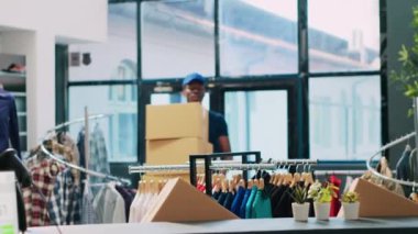 Karton kutular taşıyan Afrika kökenli Amerikan kuryesi modern butikte mağaza işçisiyle teslimat detaylarını tartışıyor. Teslimatçı tablet bilgisayarda dağıtım raporunu imzalıyor. Moda konsepti