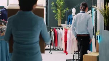 Modern butikte karton kutular taşıyan bir kuryeye yardım eden bir yönetici. Afro-Amerikan kurye, nakliye detaylarını giyim mağazasındaki işçilere açıklıyor. Moda konsepti